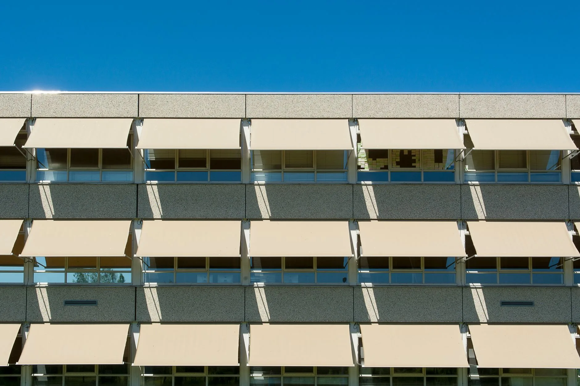 Stores extérieurs déployés sur une façade pour limiter les apports solaires d'été