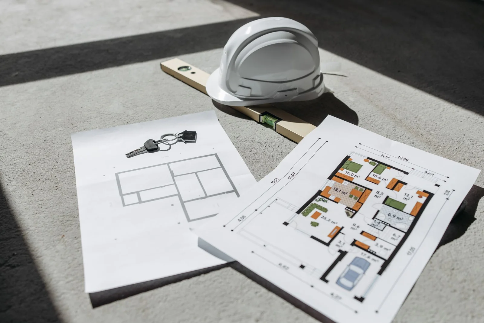 Plan de maison neuve posé sur une table avec un permis de construire et un casque de chantier